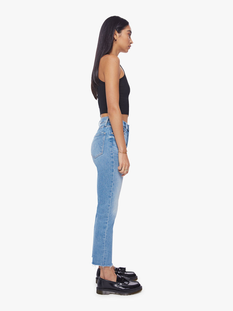 Side view of women med blue high-rise jeans with a straight leg, button fly, ankle-length inseam and a frayed hem.