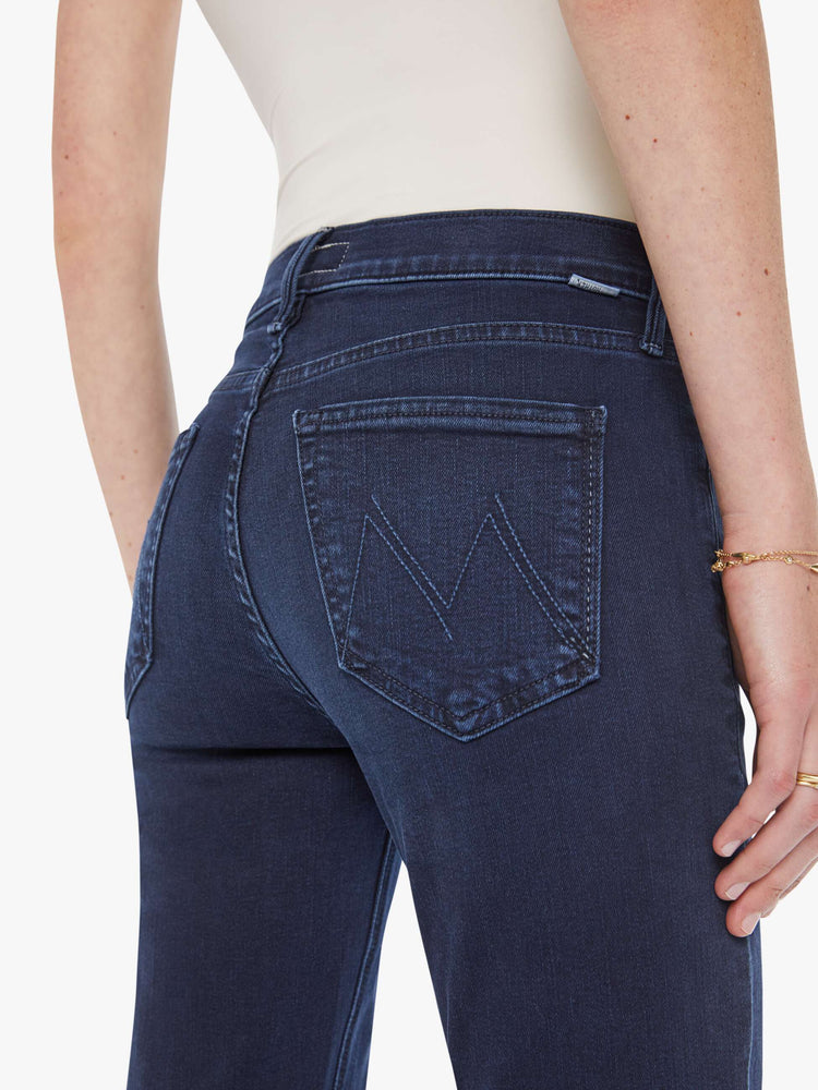 Back view of a woman in dark blue wash jeans with a mid-rise straight leg hits at the ankle with a clean hem.