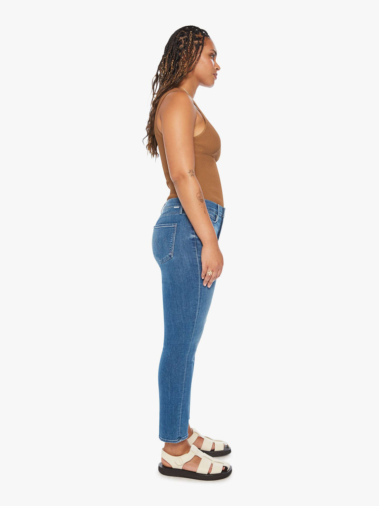 Side view of a womens medium blue wash jean featuring a mid rise, straight leg, and clean hem.