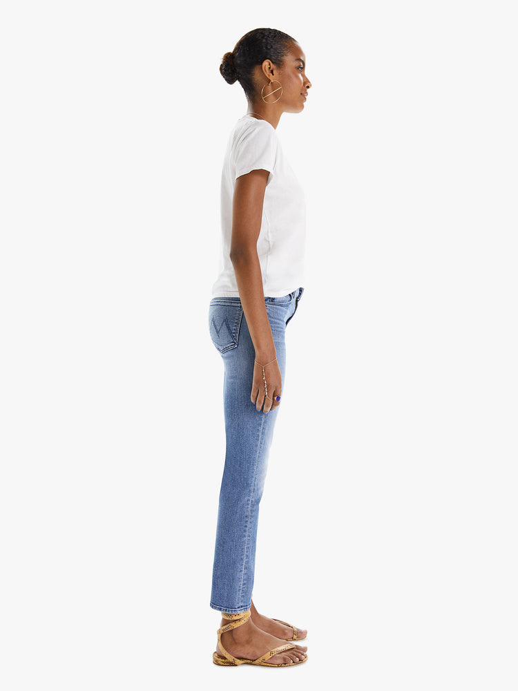 Side view of a womens classic medium blue wash denim jean featuring a mid rise, a slim straight leg, an ankle length clean hem, and subtle whiskering details.