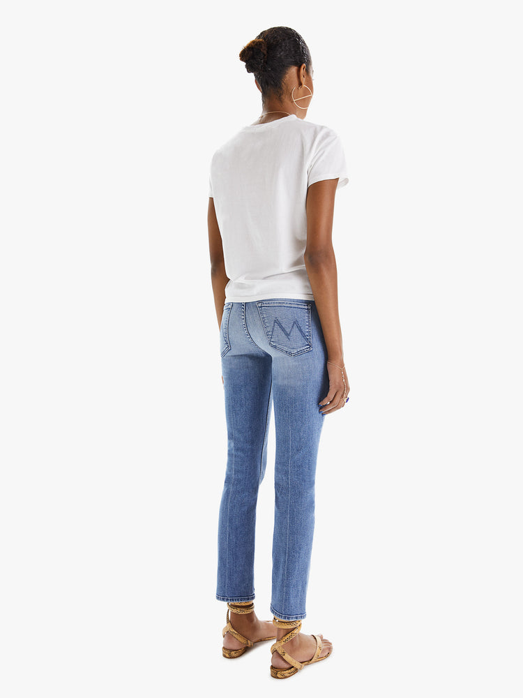 Back view of a womens classic medium blue wash denim jean featuring a mid rise, a slim straight leg, an ankle length clean hem, and subtle whiskering details.