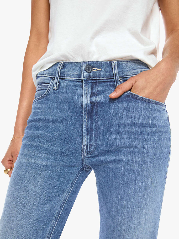 Close view of a womens classic medium blue wash denim jean featuring a mid rise, a slim straight leg, an ankle length clean hem, and subtle whiskering details.