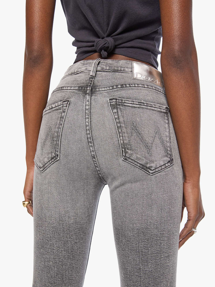 Close up view of a woman in a mid-rise straight leg has a zip fly and hits at the ankle with a clean hem in a washed grey with whiskering and fading at the knees.