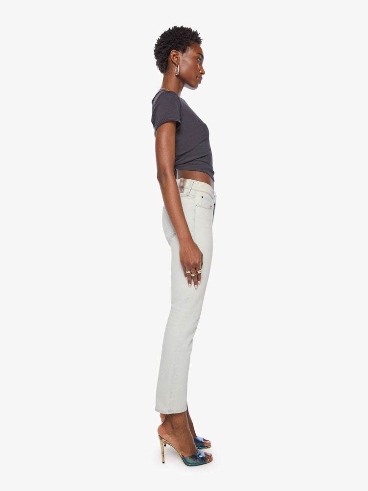 Side view of a woman in a bleached  light blue mid-rise straight leg has a zip fly and hits at the ankle with a clean hem. 