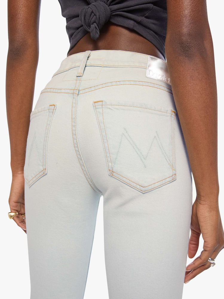 Back close up view of a woman in a bleached  light blue mid-rise straight leg has a zip fly and hits at the ankle with a clean hem. 