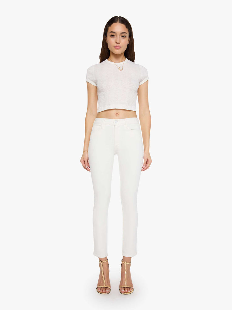 Front view of a model wearing white denim pants with a mid rise, slim straight leg, and a clean hem.