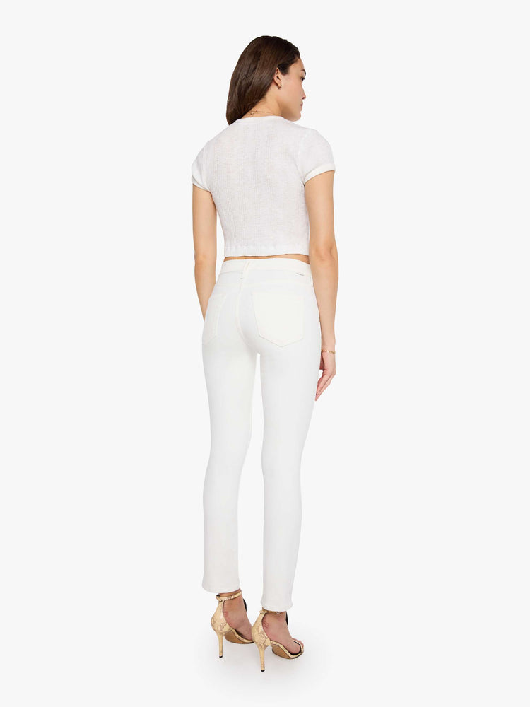 Back view of a model wearing white denim pants with a mid rise, slim straight leg, and a clean hem.