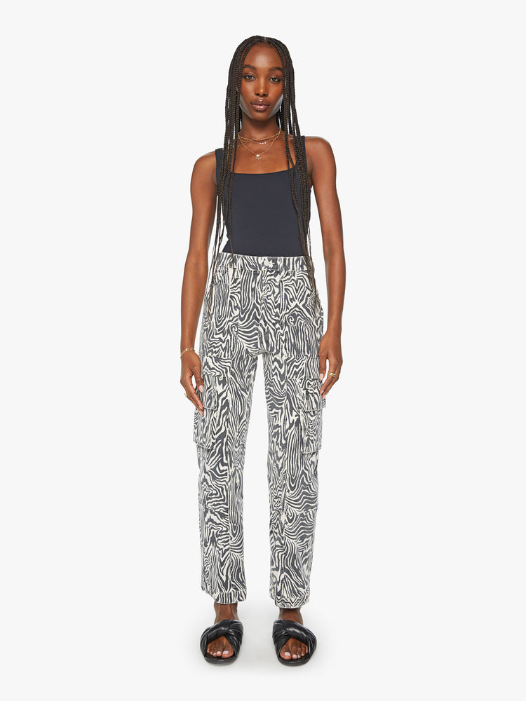 Front view of a woman high waisted cargo pant with a barrel leg, patch pockets and a long inseam with snaps at the hem with black and white zebra print.