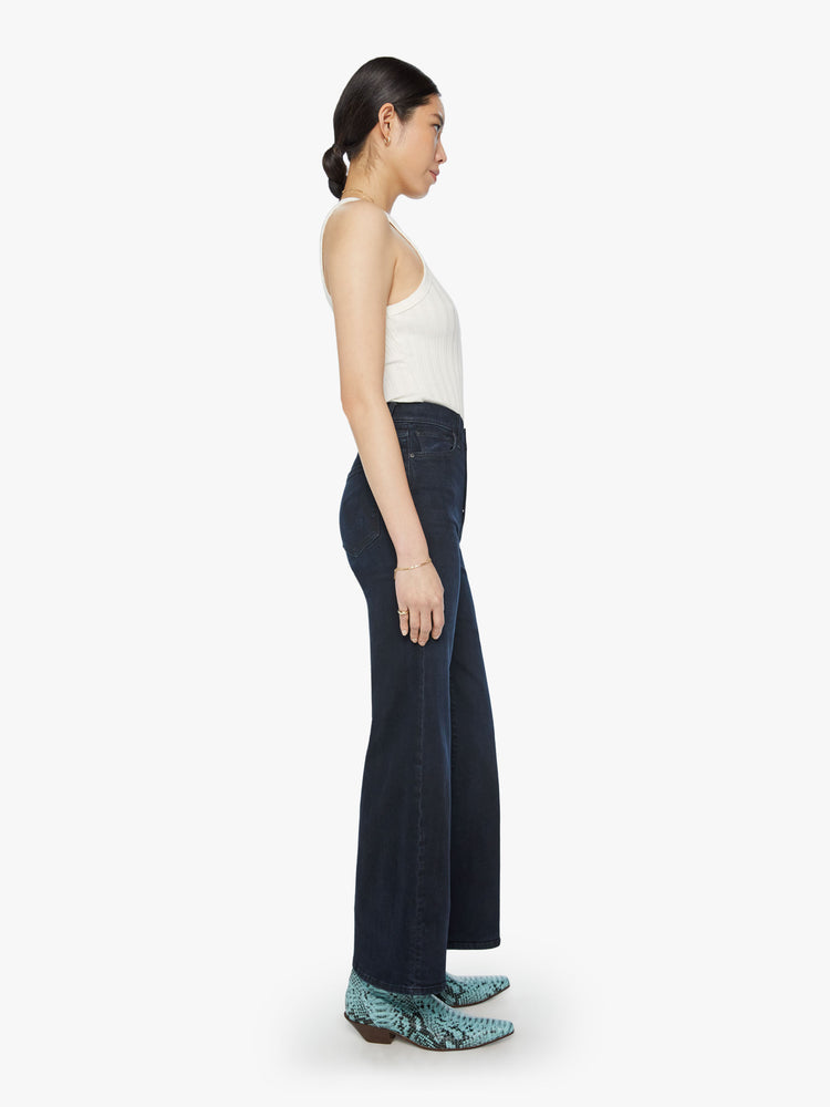Side view of a woman high-waisted wide leg has a button fly, 31-inch inseam and clean hem in dark blue wash.