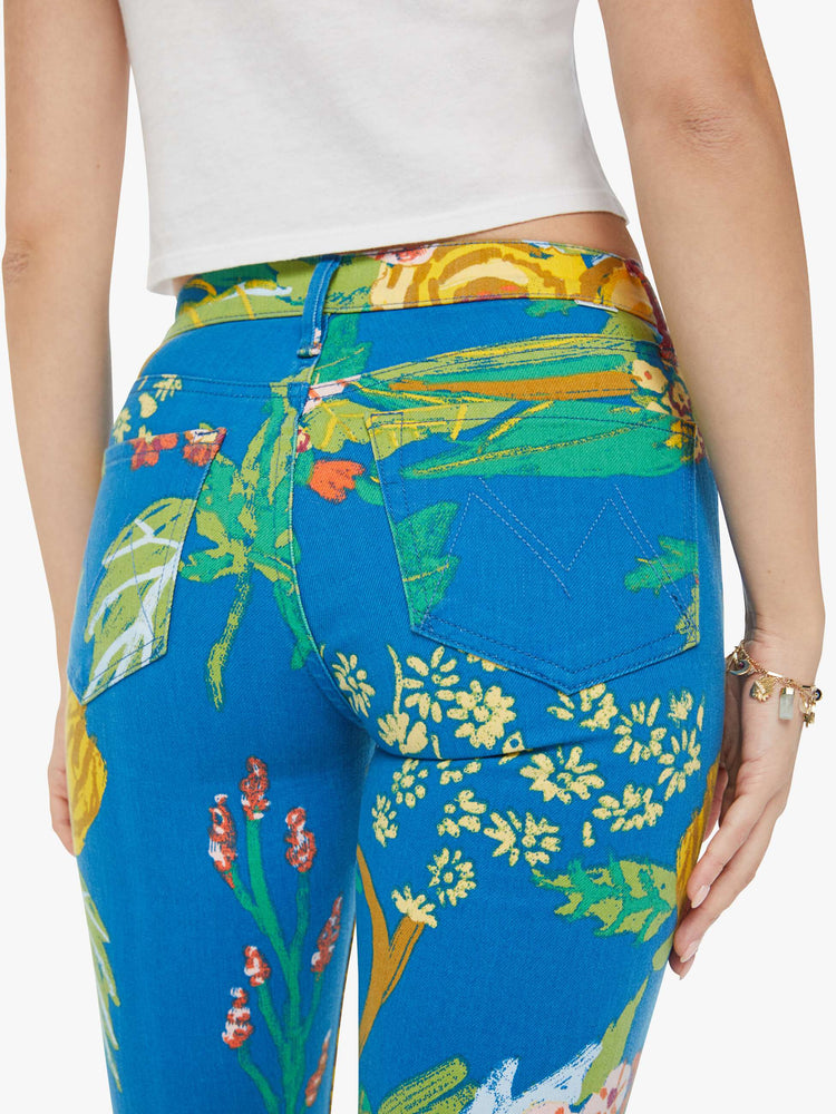 Swatch view of a woman in bright blue tropical floral print straight leg jeans with a cropped hem and styled with a white tank top. 