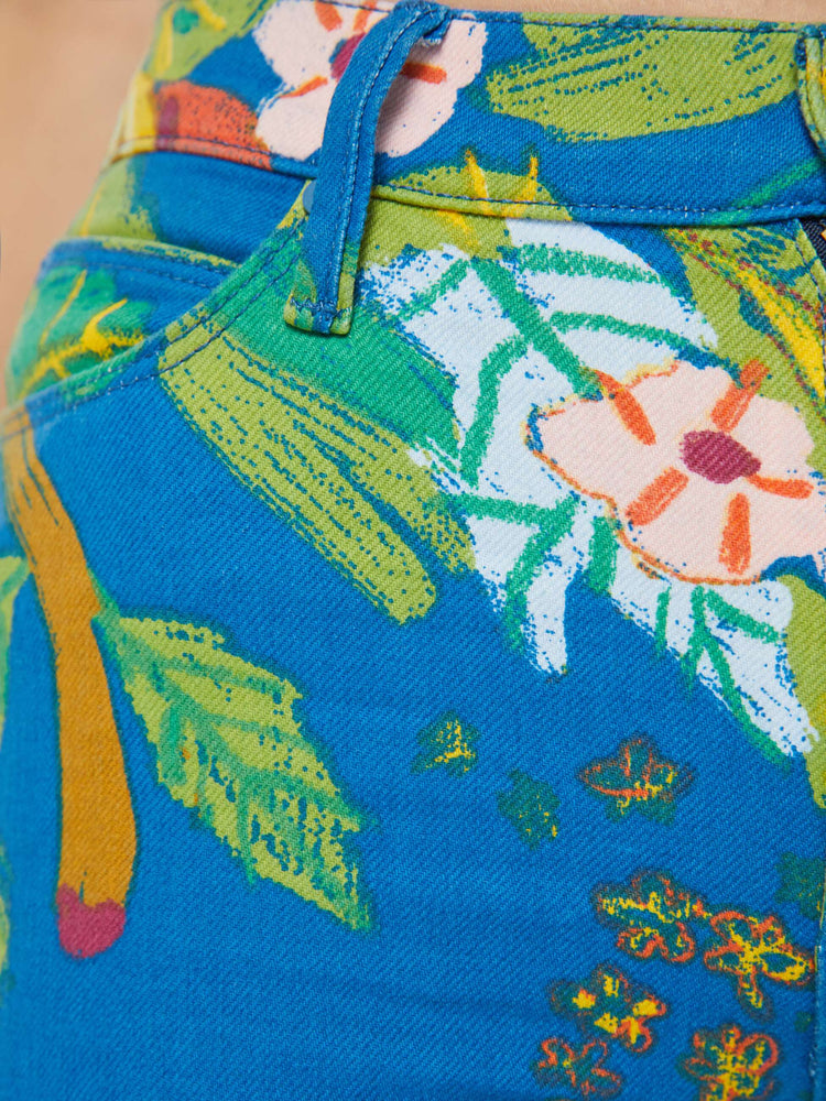 Detailed view of a woman in bright blue tropical floral print straight leg jeans with a cropped hem.