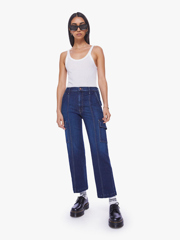 Front view of a woman dark blue wash high-waisted ankle-length pants with a wide straight leg, cargo pockets and seams down the front.