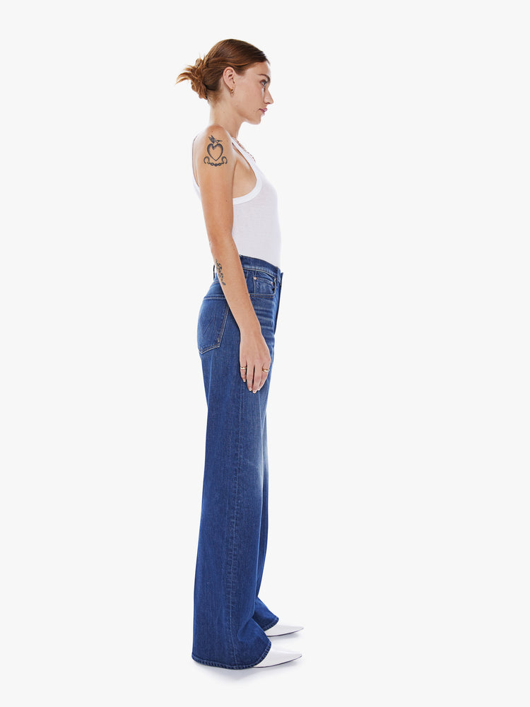 Side view of a woman super wide-leg jeans with a high rise and a long 34-inch inseam in a blue hue.