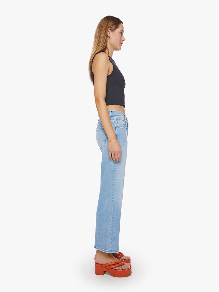 Side view of a woman high-waisted jeans with a loose wide leg and an ankle-length inseam in a light blue wash.