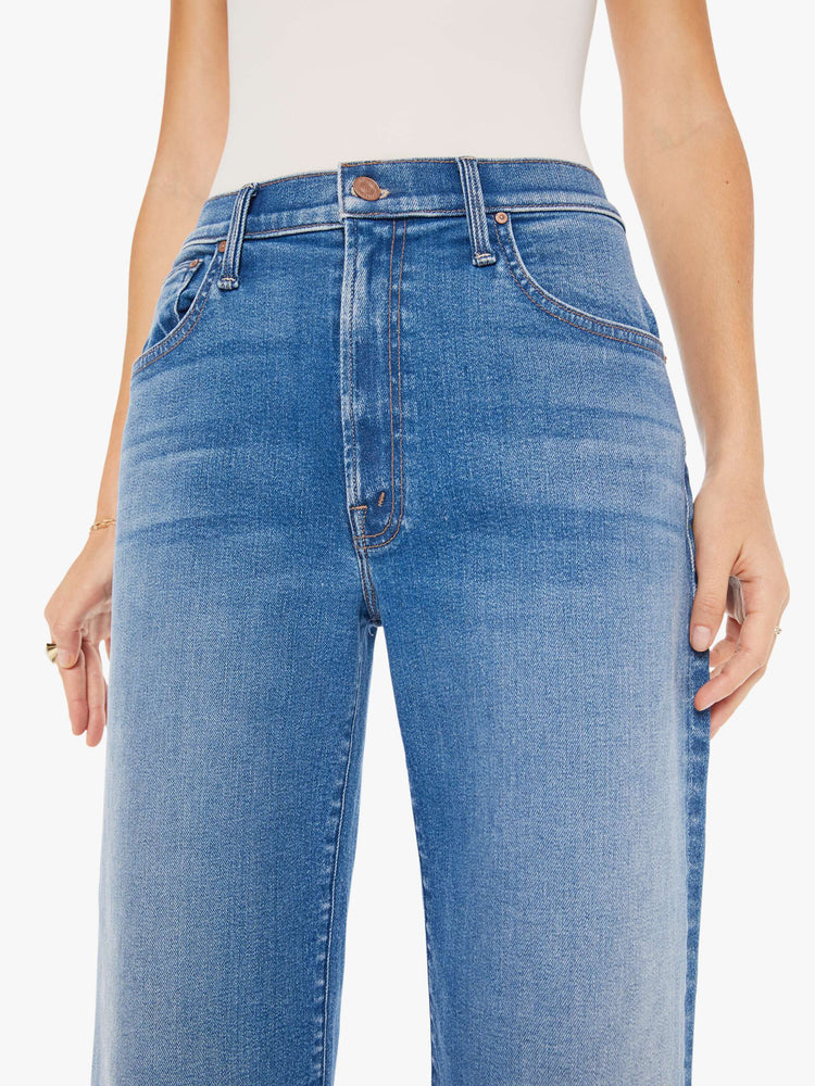 Close up view of a woman igh-waisted jeans with a loose wide leg and an ankle-length inseam in a medium blue wash.