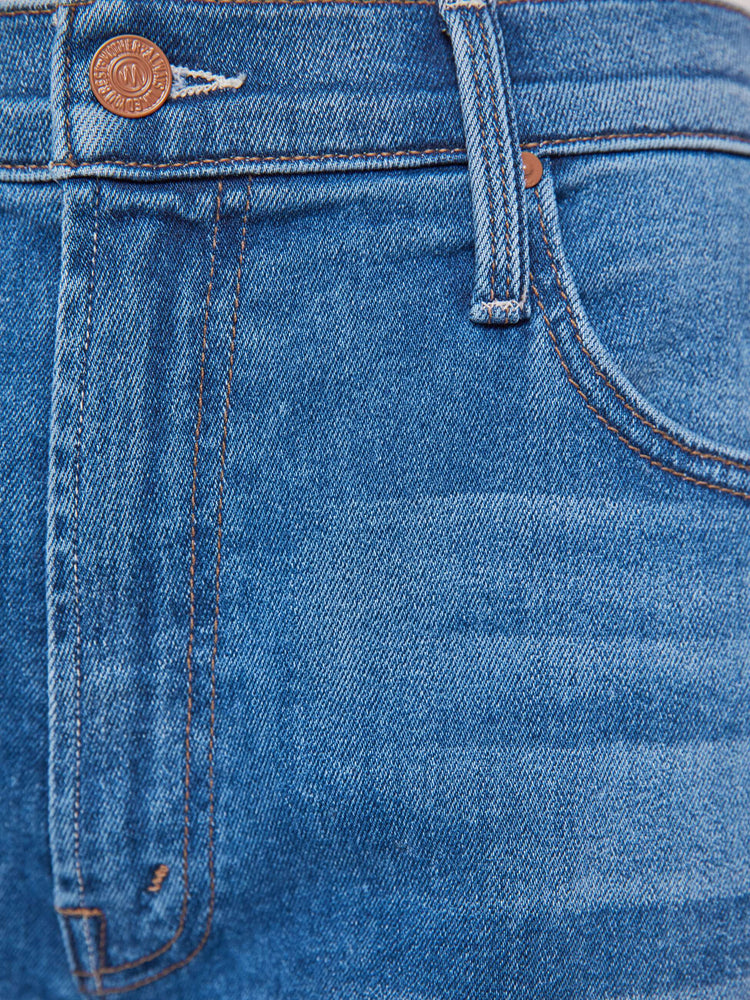 Swatch view of a woman in a mid blue jean that sit lower on the hips with a zip fly, loose wide leg and a clean ankle-length inseam.