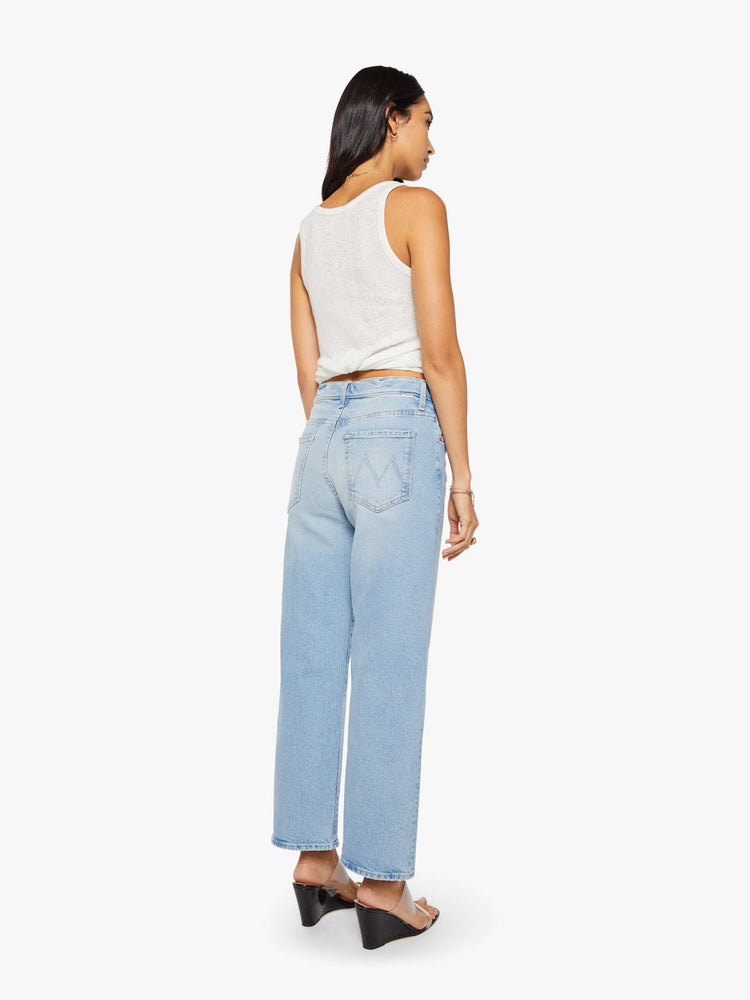 Back view of a woman in a light blue jeans designed to sit lower on the hips with a zip fly, loose straight leg and a clean ankle-length inseam.