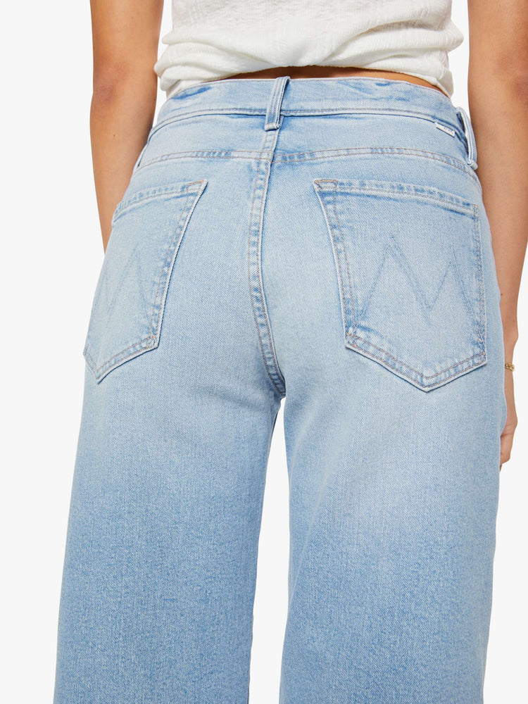 Close up view of a woman in a light blue jeans designed to sit lower on the hips with a zip fly, loose straight leg and a clean ankle-length inseam.