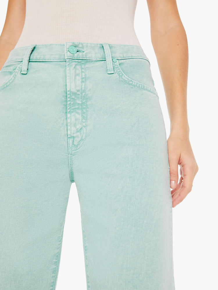 Front close up view of a woman wearing a light teal acid wash pant featuring a wide leg.