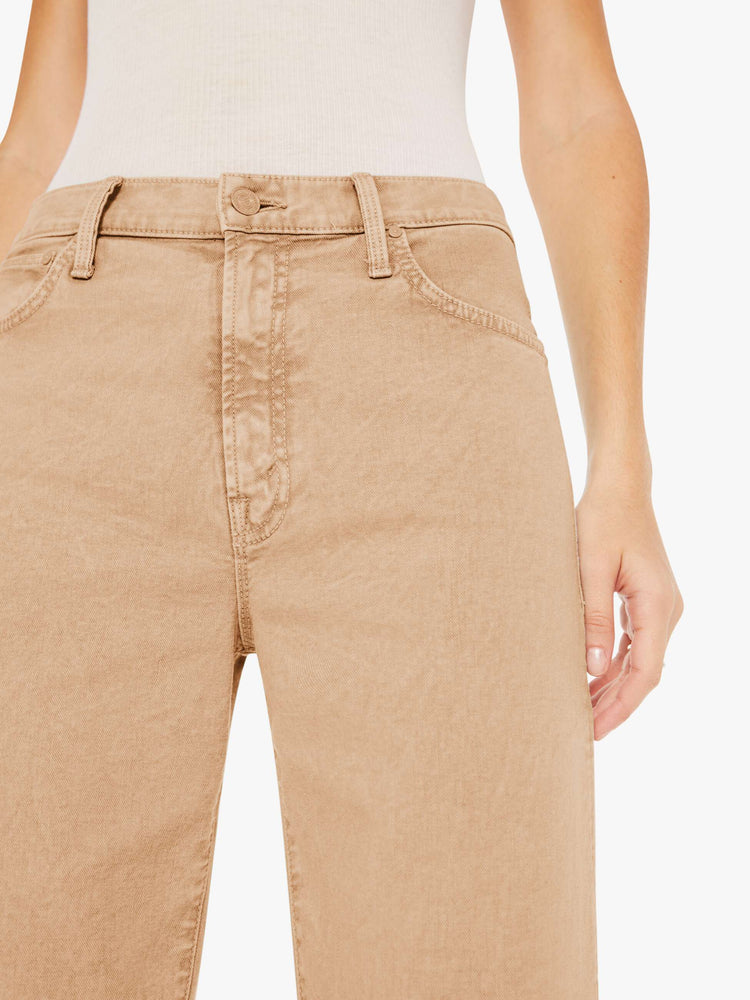 Front close up view of a woman wearing a light brown acid wash pant featuring a wide leg and ankle length hem.