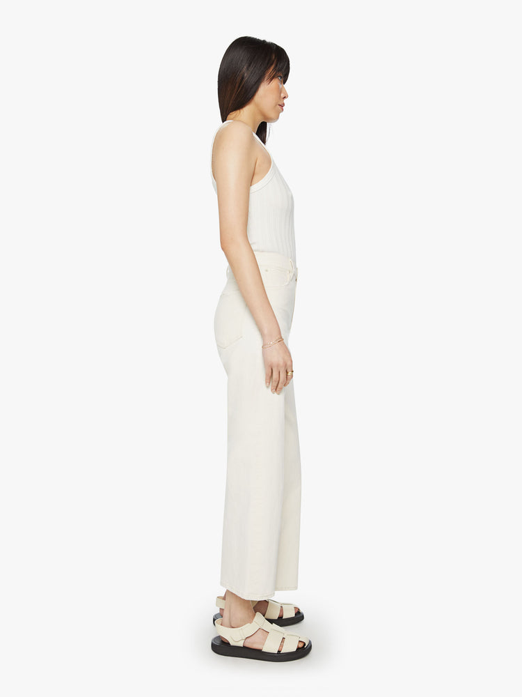 Side view of a woman high waisted jeans with a loose wide leg and an ankle-length inseam in a creamy white wash.