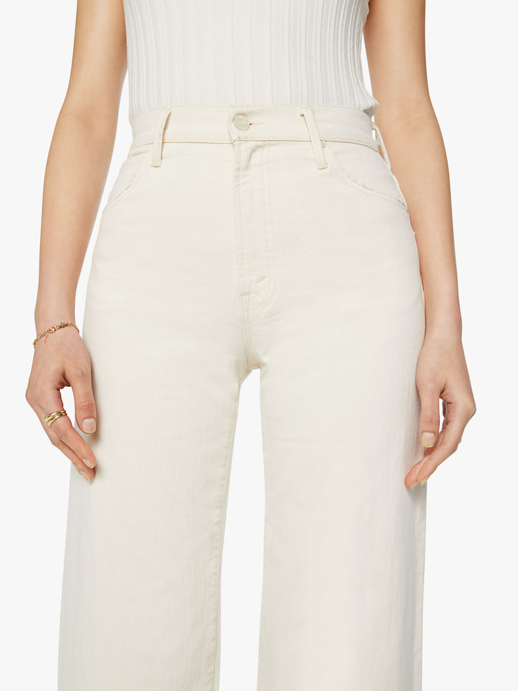Waist close up view of a woman high waisted jeans with a loose wide leg and an ankle-length inseam in a creamy white wash.