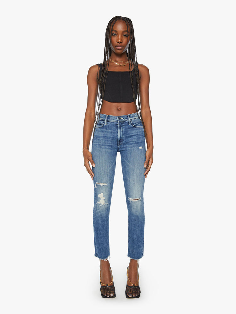 FULL BODY FRONT VIEW OF MID RISE, ANKLE LENGTH STRETCH JEANS WITH FRAYED HEM, WHISKERING, AND DISTRESSED THROUGHOUT