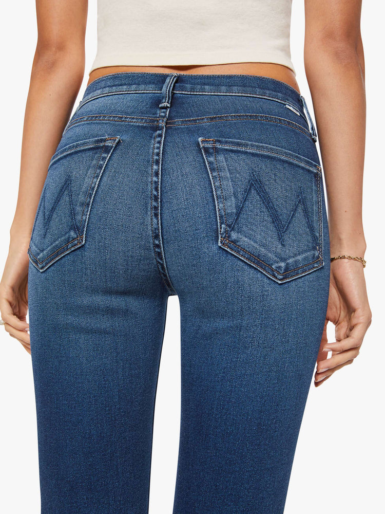 Close up view of a woman in  dark blue mid-rise straight leg hits at the ankle with a frayed hem.
