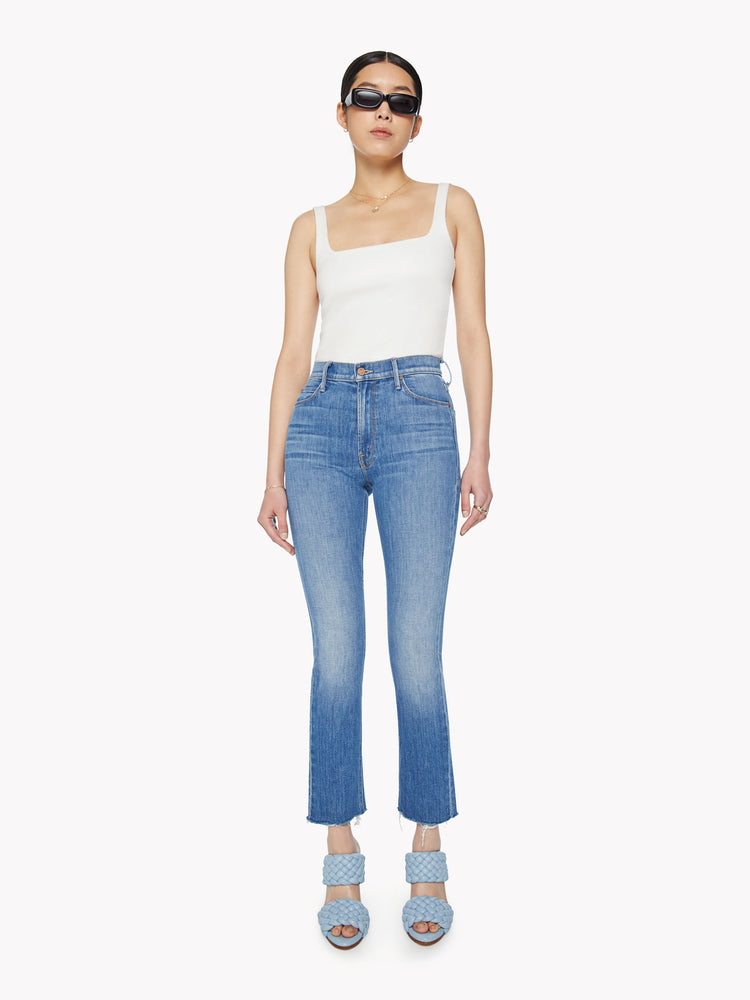 Front view of a woman mid-rise straight leg with an ankle-length inseam and a frayed hem in a mid-blue wash.