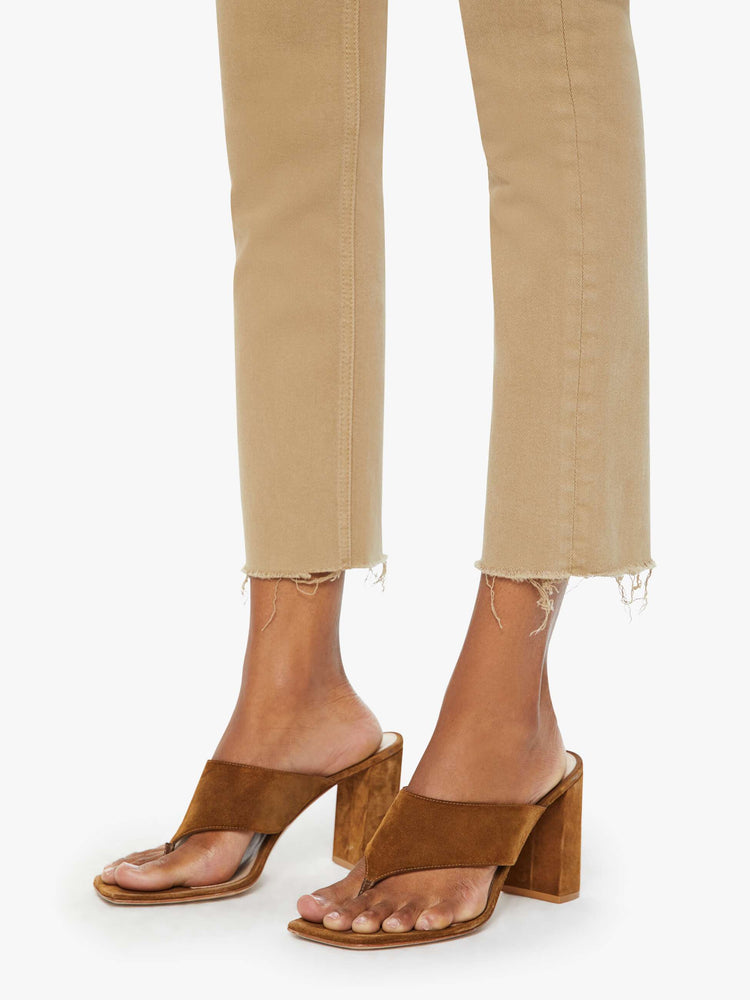 Side close up view of a womens brown pant featuring a mid rise and a straight leg with a frayed hem.