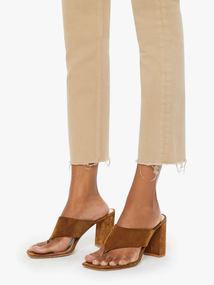 Front close up view of a womens brown pant featuring a mid rise and a straight leg with a frayed hem.