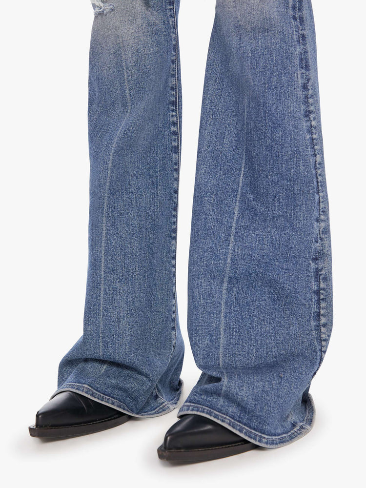 Hem close up  view of a medium blue flare with distressed knees and a long clean hem.