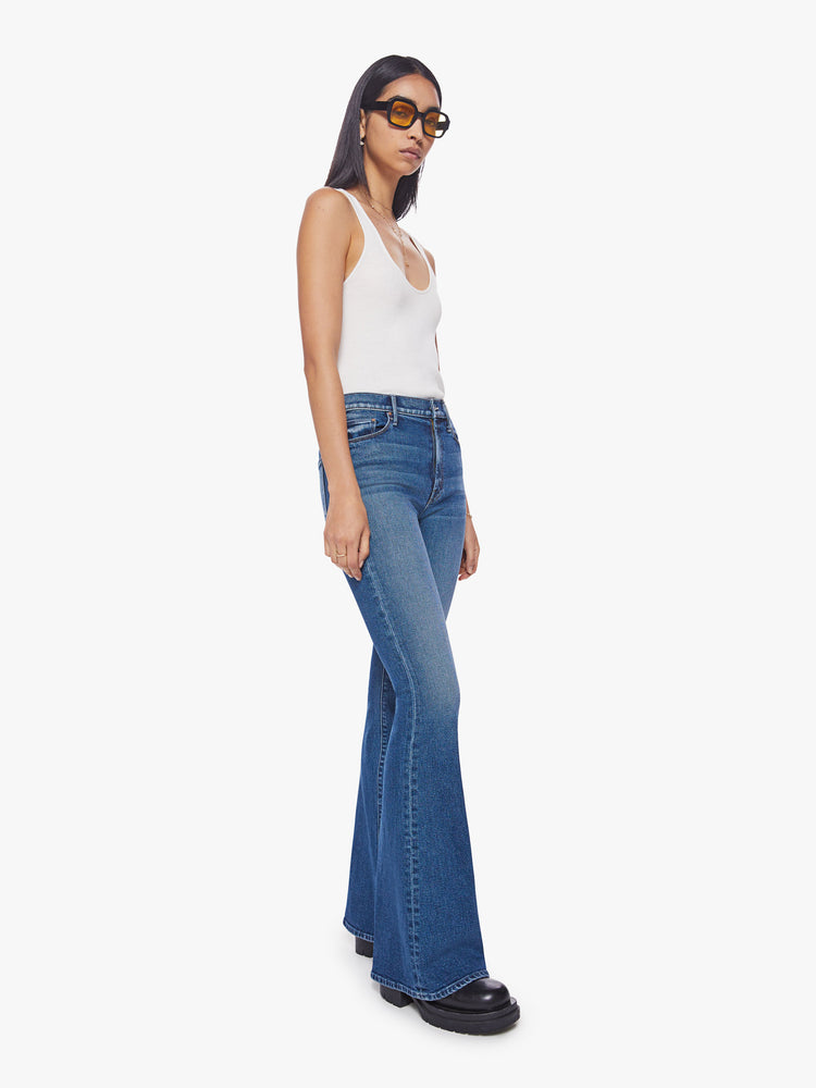 Side angle view of a woman high-rise flare with a long 34.5-inch inseam and a clean hem in a classic blue hue.