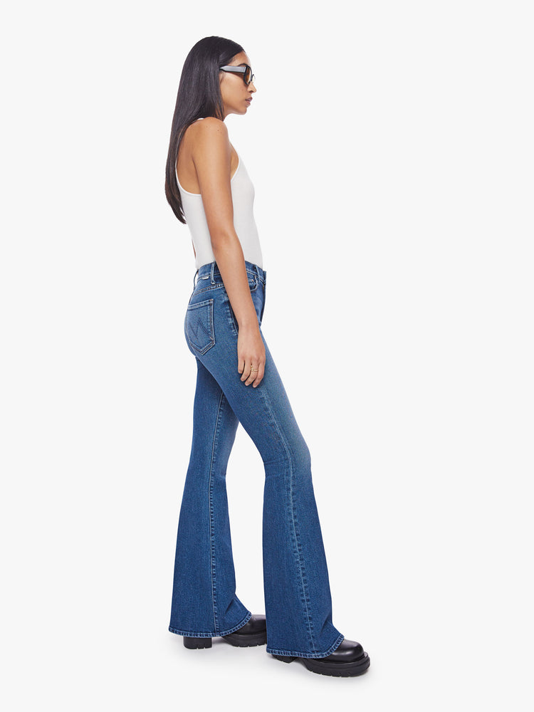 Side view of a woman high-rise flare with a long 34.5-inch inseam and a clean hem in a classic blue hue.