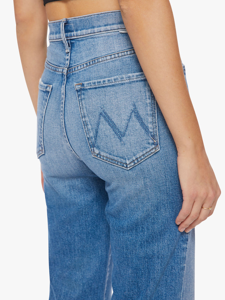 Close up back waist view of a woman super high-waisted straight-leg jeans with a V-shaped back hem and a shorter hem in the front in a light blue wash.