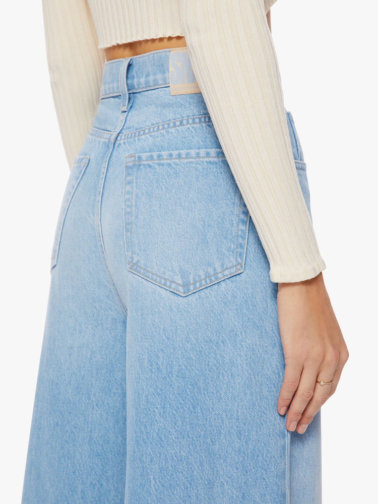 Waist close up view of a woman super high-waisted jeans feature a loose, full leg and a long 34-inch inseam in a light blue wash.