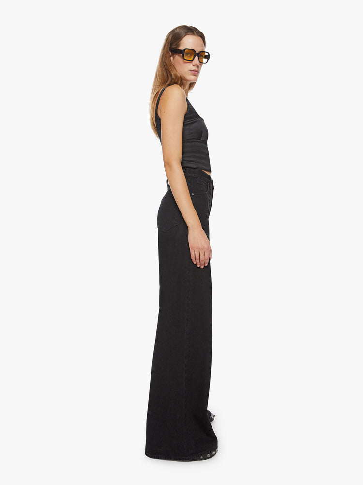 Side view of a woman black wide leg with a super high rise jeans feature a loose, full leg and a long 34-inch inseam.