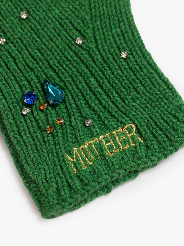 Close up of  fingerless gloves with ribbing throughout and MOTHER's name embroidered at the wrist in a green color.