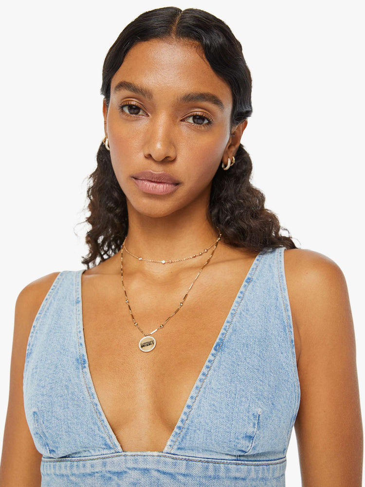 Swatch view of a woman in a light blue denim bralette with a deep V-neck, thick underband, adjustable straps and a button closure in the back.