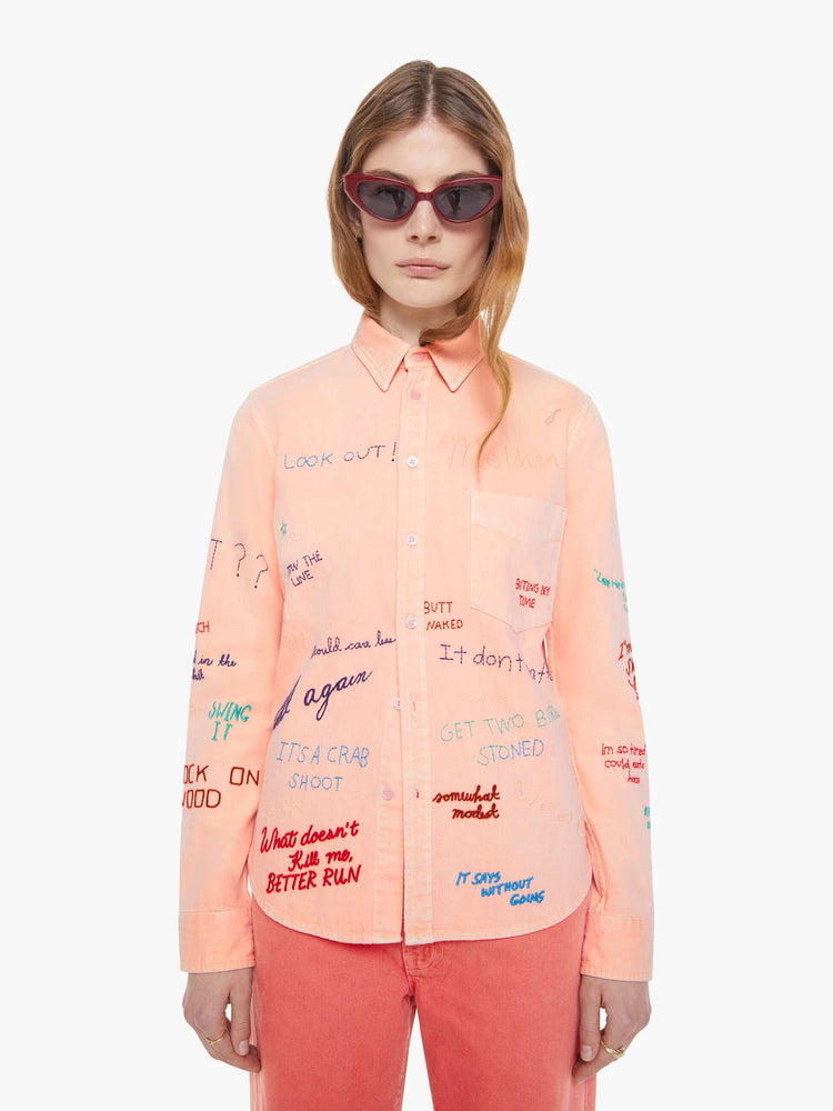 Font view of a woman in a faded orange with embroidery button-up blouse with patch pockets and a curved hem.