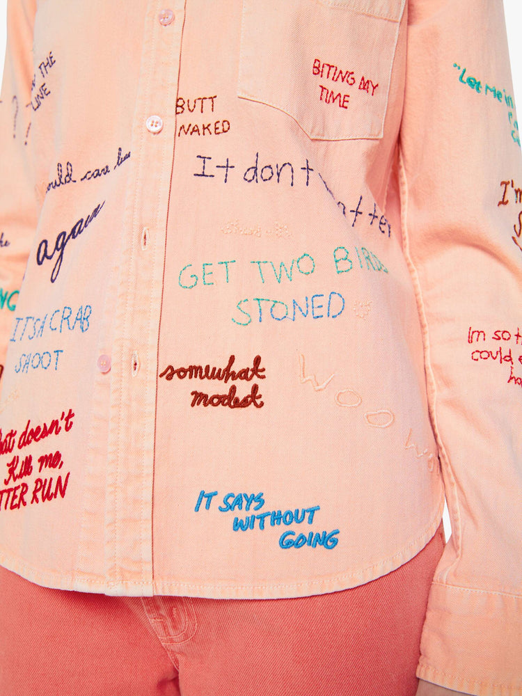 Close up view of a woman in a faded orange with embroidery button-up blouse with patch pockets and a curved hem.