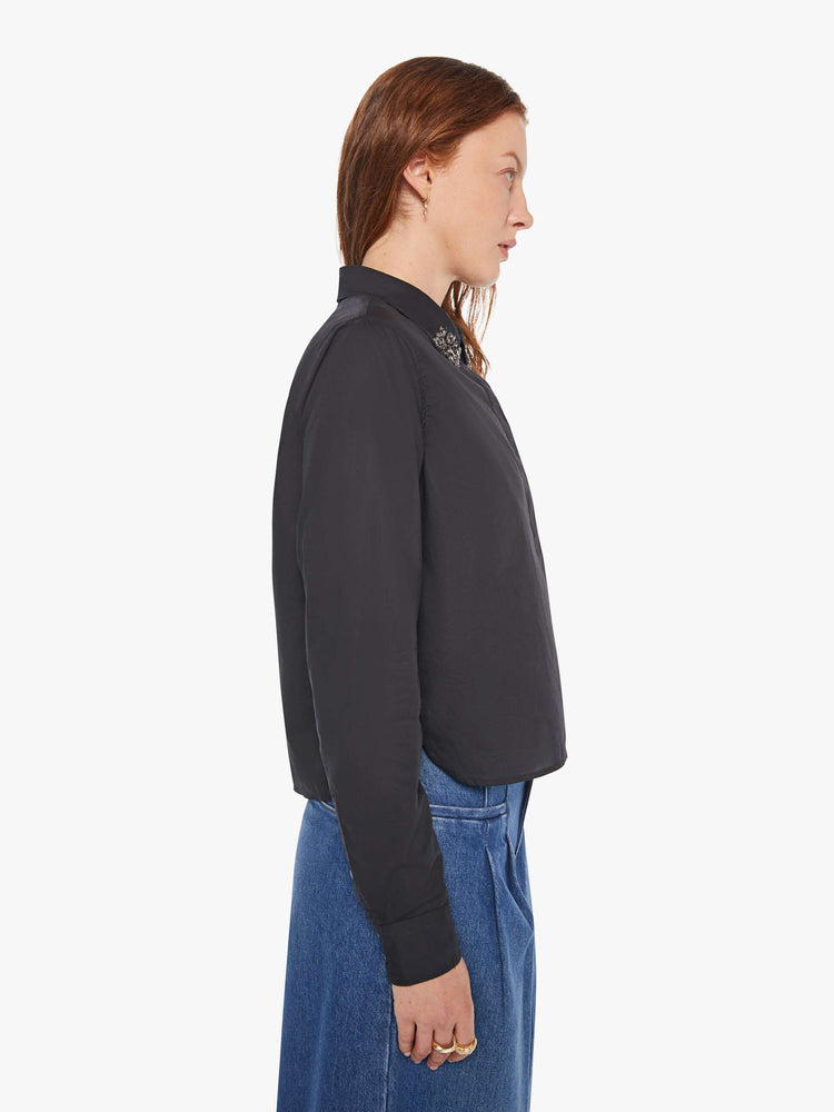 Side view of a woman in a black button up with an embellished collar.