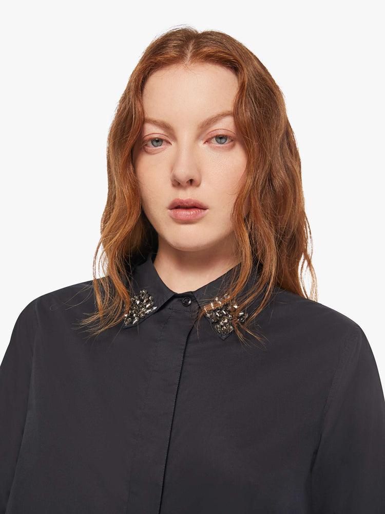 Close up view of a woman in a black button up with an embellished collar.