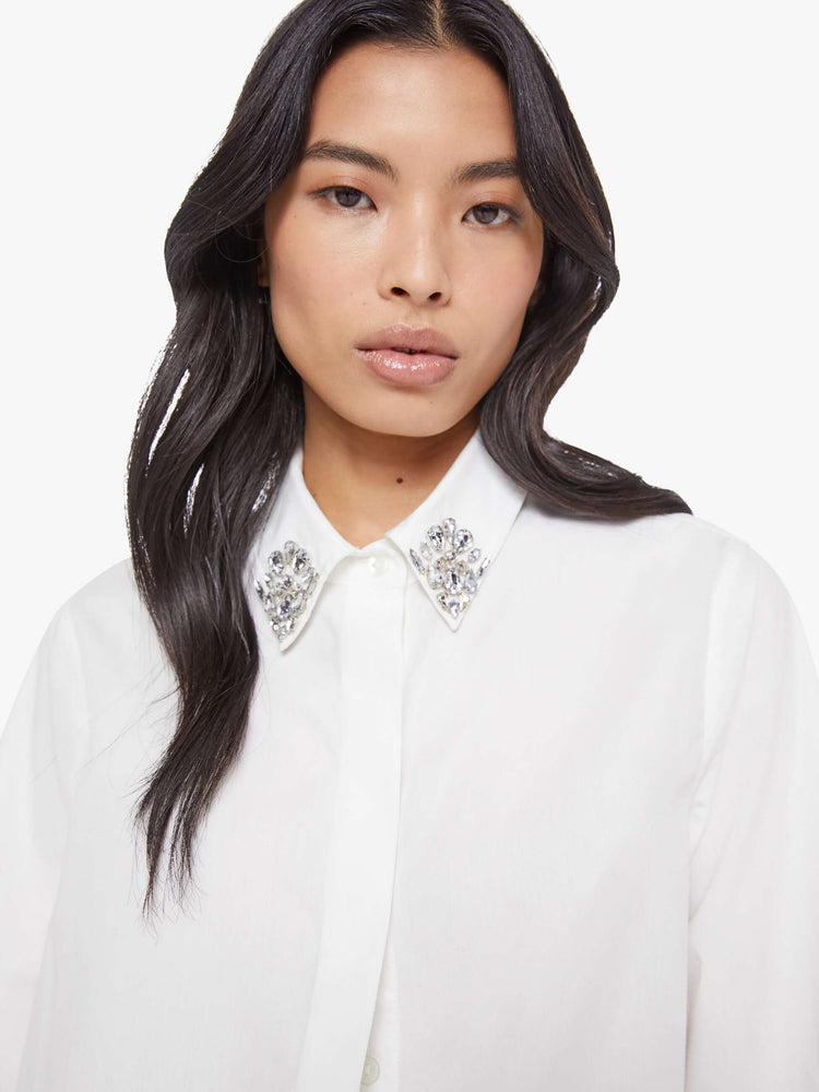 Close up view of a woman in a white twist on the classic button-up with long sleeves, a hidden button panel and a cropped fit.