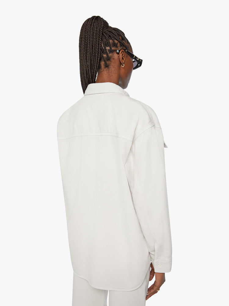 Back view of a woman oversized button-up with drop shoulders, patch pockets and a curved hem in an off white hue.