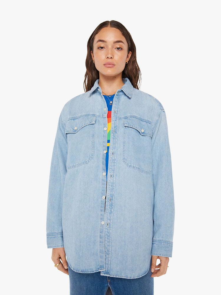Front view of a woman oversized button-up with drop shoulders, patch pockets and a curved hem in a light blue wash with white buttons.