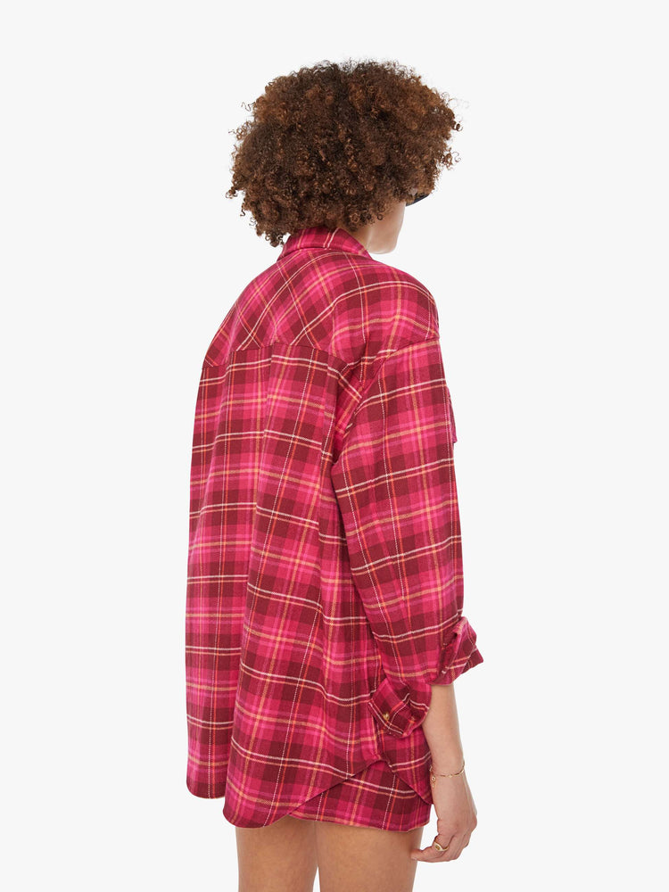 Back view of a woman in a hot pink oversized button-up with drop shoulders, patch pockets and an extra-long curved hem.