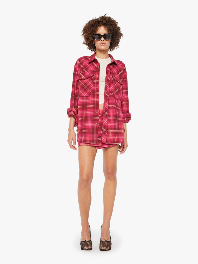 Full body view of a woman in a hot pink oversized button-up with drop shoulders, patch pockets and an extra-long curved hem.