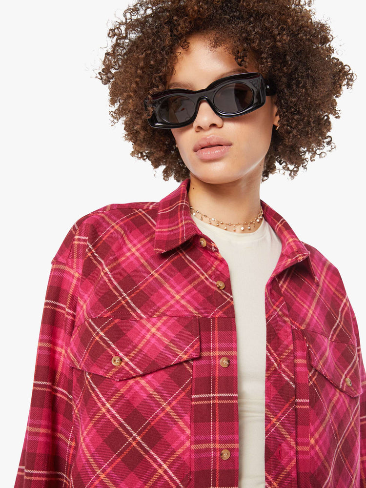 Close up view of a woman in a hot pink oversized button-up with drop shoulders, patch pockets and an extra-long curved hem.