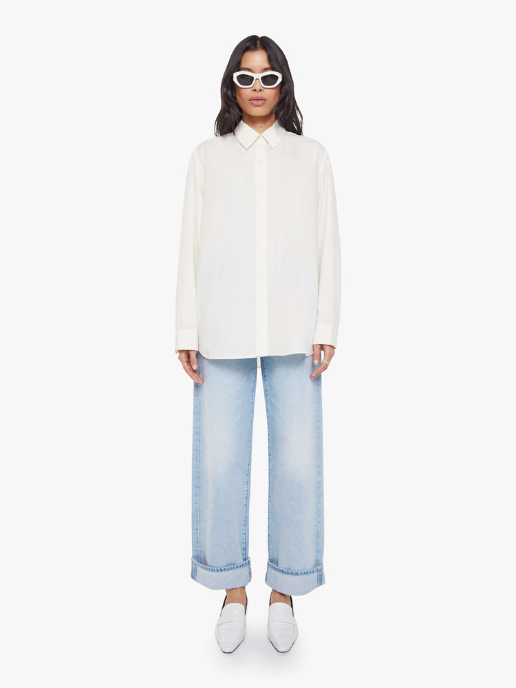 Full body view of a woman in an antique white with a chain stitched MOTHER on front and back oversized button-up blouse with drop shoulders and a curved hem.